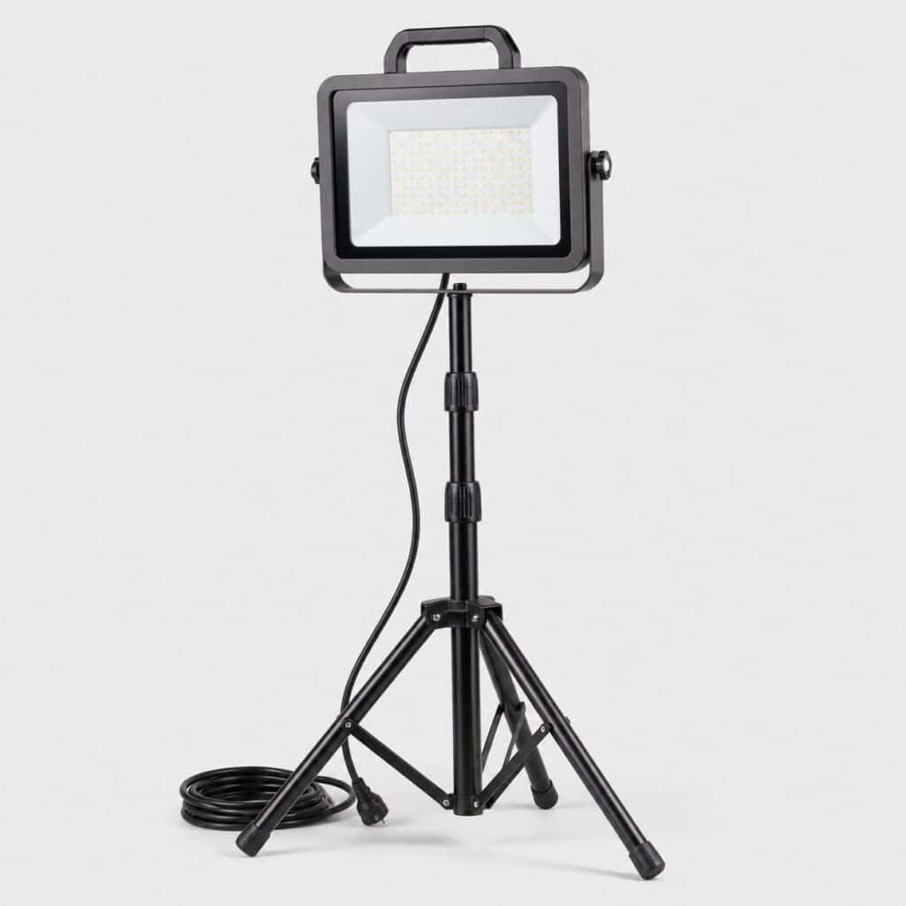 Projecteur LED de chantier robuste sur trépied télescopique, vue de trois quarts sur fond clair