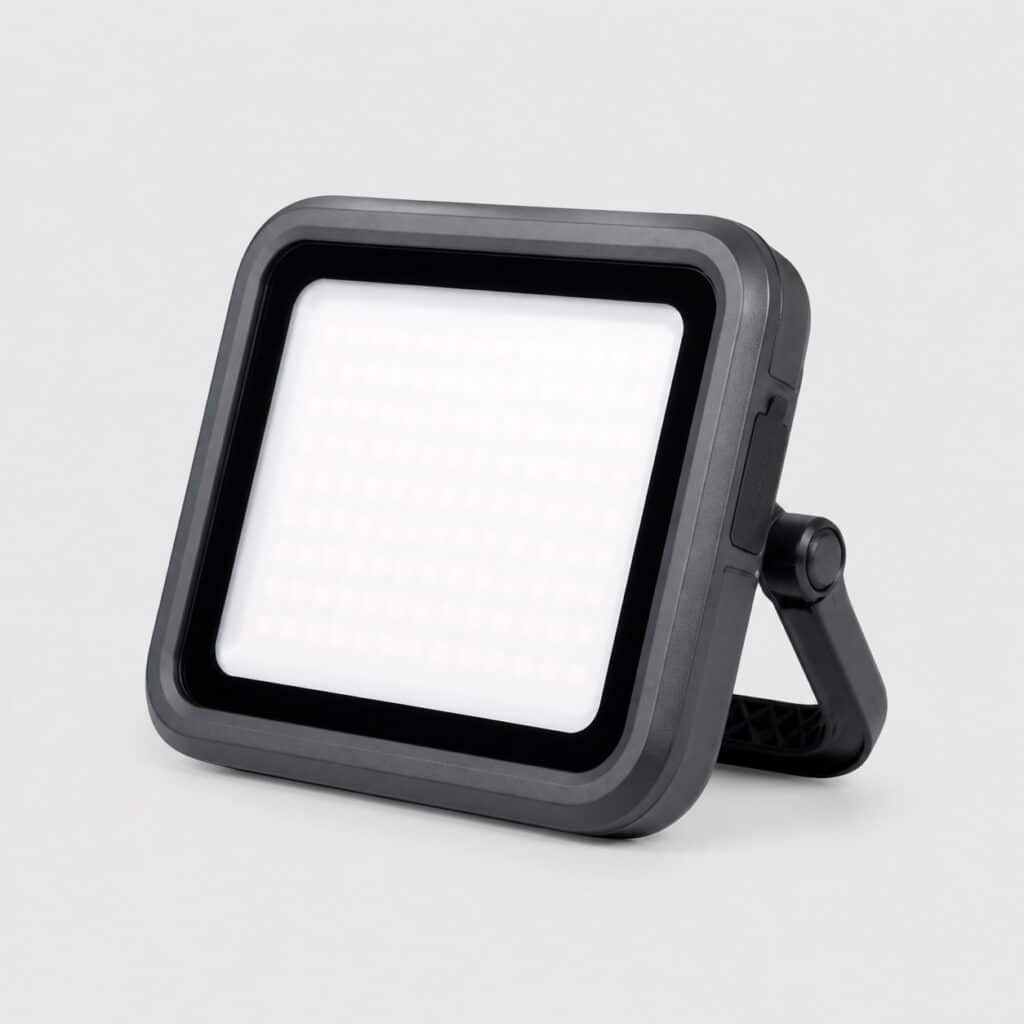 Projecteur LED portable rechargeable compact à poignée-pied, vue de trois quarts sur fond clair